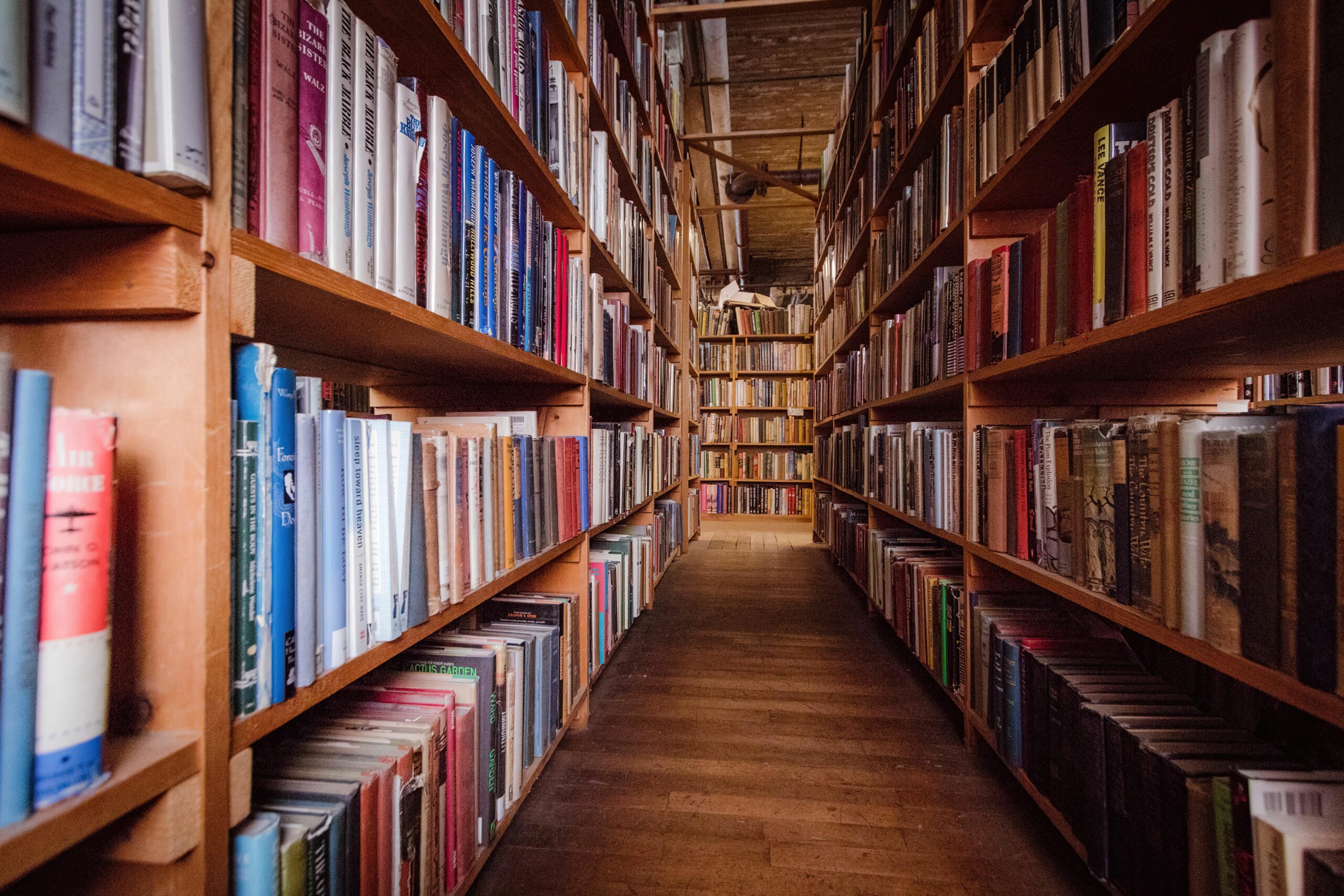 Photo of looking down an aisle of old wooden bookshelves inside a library.