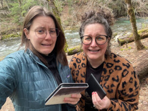 Photo of Maegan and Natalie, both White women with glasses, with their Kindles and sad, scared and trepidatious looks on their faces.