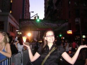 Photo of Maegan from 2007 standing under a large Harry Potter banner in Times Square.