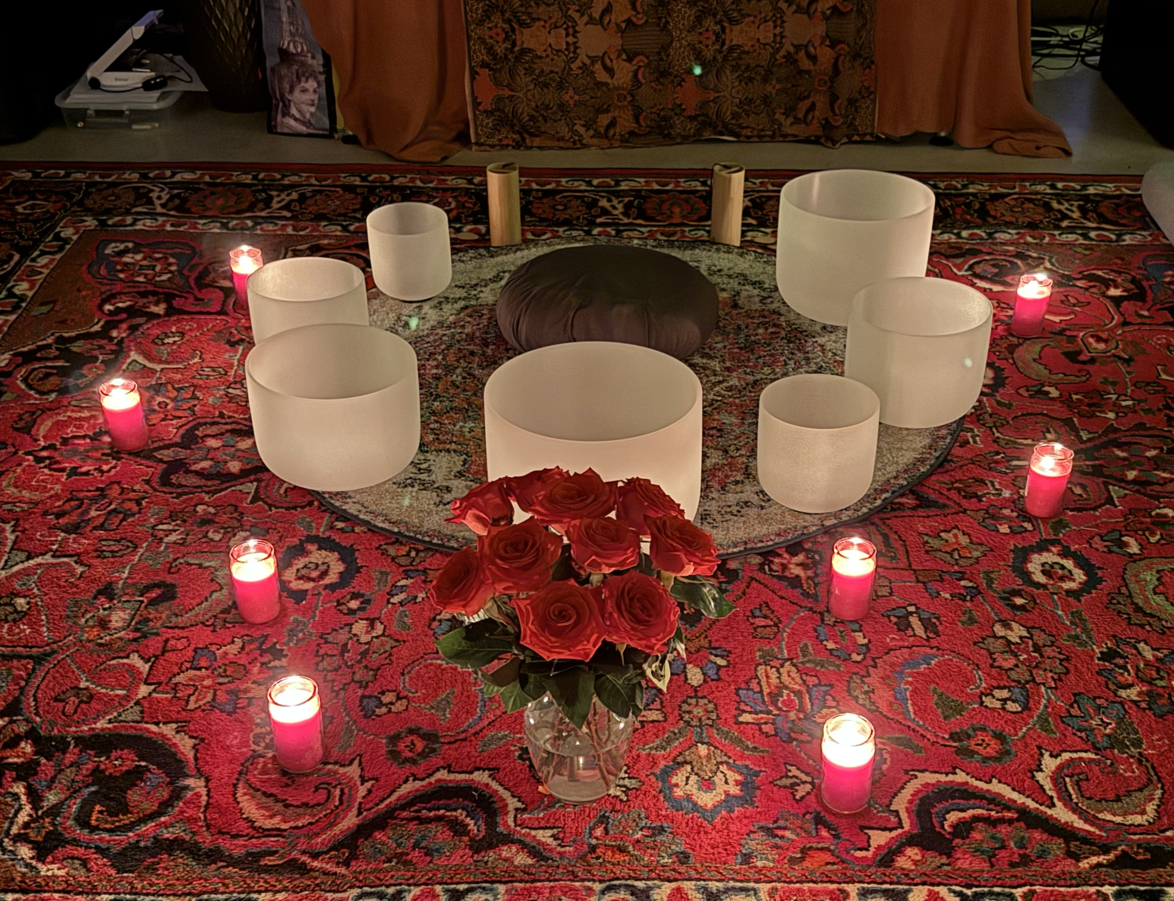 A sound bath setup with crystal bowls and koshi chimes surrounded by flowers and candles.
