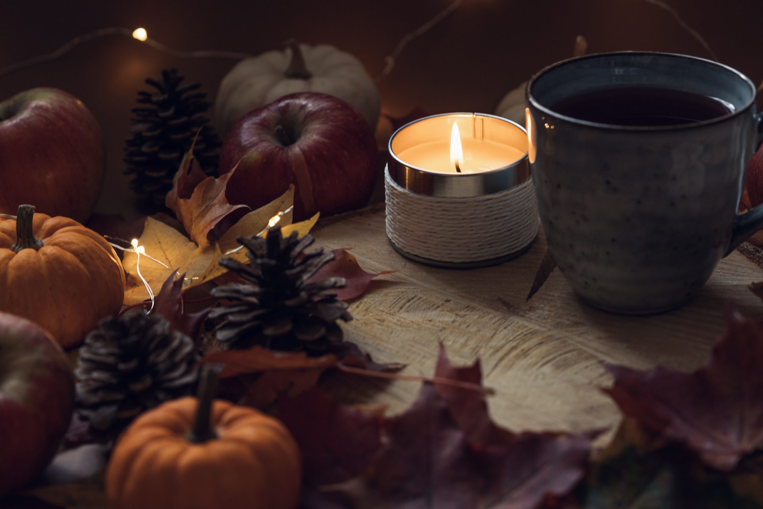 A soft-lit scene with candles, autumn foliage, and symbolic ritual items representing grief, release, and seasonal renewal.